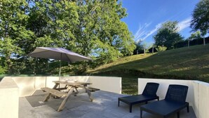 Een terras buiten met een picknicktafel en twee loungestoelen.