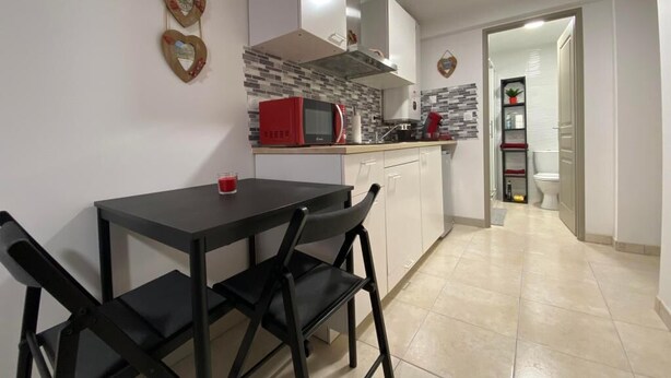 A compact kitchen with a dining table and chairs, a microwave, and a sink. - Aitzina Studio - Downtown (CAMBO LES BAINS)