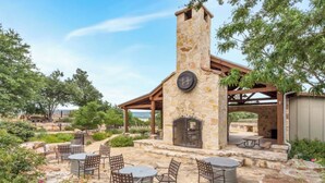 Um pátio de pedra com área de estar externa e lareira de pedra.