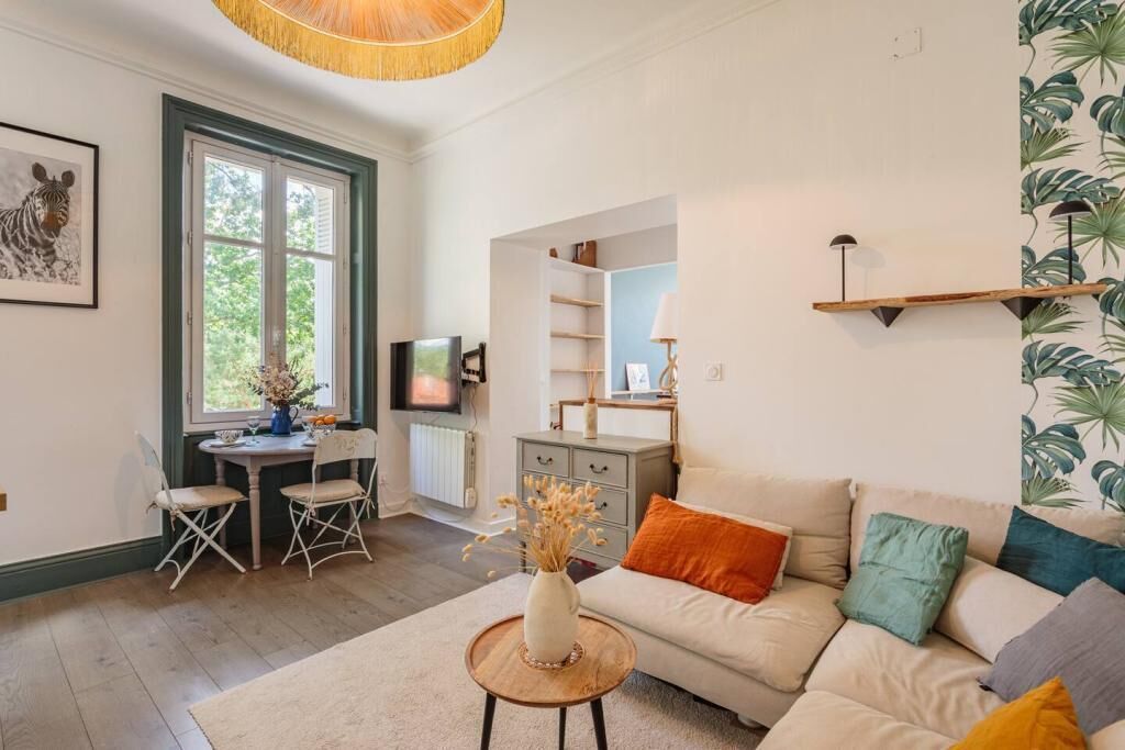Un salon comprenant un canapé, une table basse, un téléviseur, un bureau avec des chaises et une bibliothèque.
