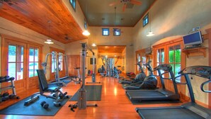 Een fitnessruimte met cardioapparaten, gewichten en een houten inrichting.