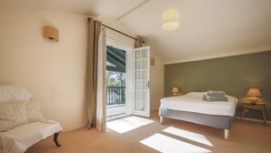 A bedroom with a bed, a chair, a nightstand, a lamp, and a door leading to an outdoor area.