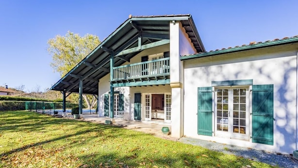 A two-story building with a balcony, a covered porch, and a door with shutters.