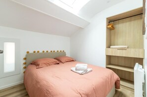 Une chambre à coucher avec un lit, une lucarne, une armoire et une fenêtre.