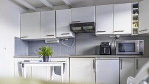 A modern kitchen with white cabinets, a built-in oven, a microwave, and a coffee machine.