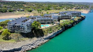 Un hotel frente al mar con varias construcciones, una piscina y un litoral rocoso.