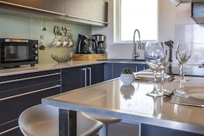A modern kitchen with a built-in microwave, coffee maker, and kettle.