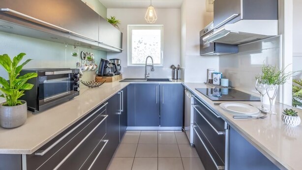 A modern kitchen with a built-in oven, a sink, and a window. - Le Lodge de Boucau - T2 with Balcony (BOUCAU)