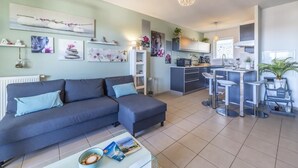A modern living room with a sofa, coffee table, and artwork on the walls. - Le Lodge de Boucau - T2 with Balcony (BOUCAU)