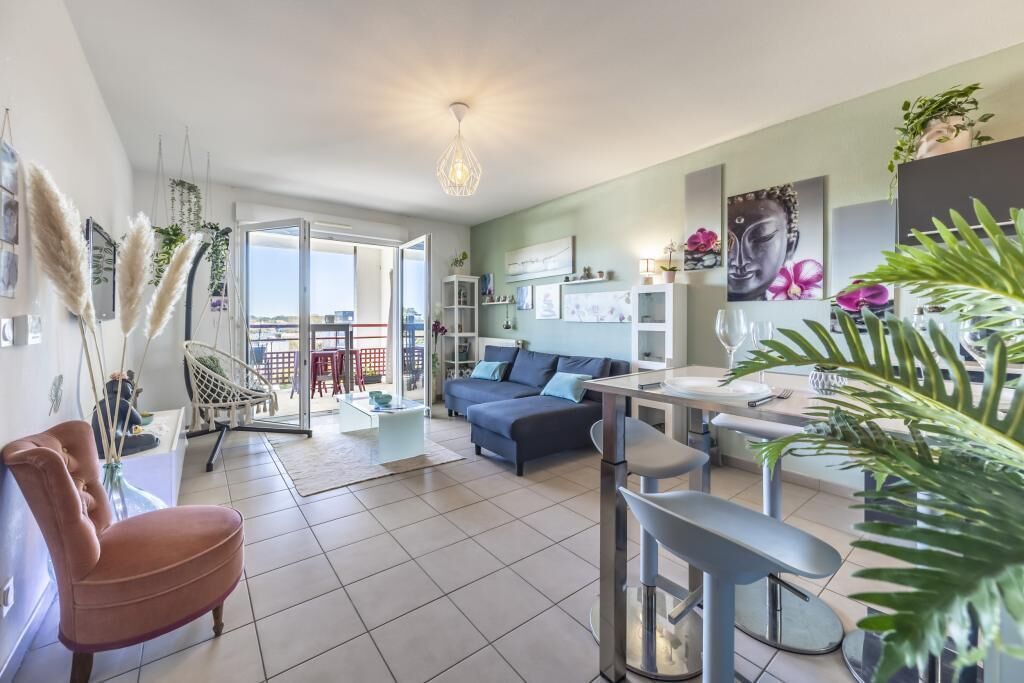 A modern living room with a sofa, dining table, chairs, and a balcony with a view.