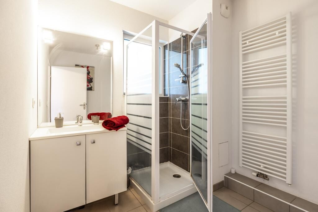 A bathroom with a shower, a sink, and a mirror.