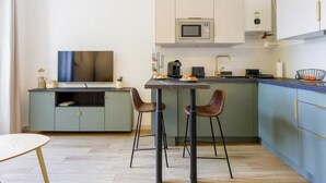 Une cuisine compacte équipée d’un four à micro-ondes, d’une machine à café et d’un petit coin repas avec des tabourets.