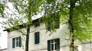 Un bâtiment doté de nombreuses fenêtres et d’une porte, des voitures garées et un poteau en premier plan.