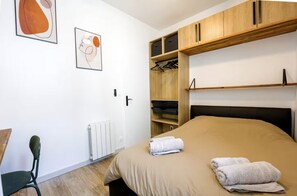 Une chambre à coucher avec un lit, une armoire en bois, un radiateur et une chaise.