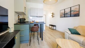 Une cuisine moderne avec un îlot central, des tabourets de bar, une table à manger, un canapé et un tableau au mur.
