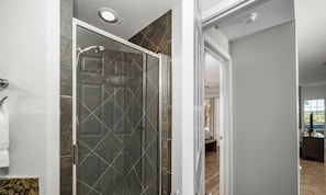 A modern bathroom with a glass shower door, a visible towel rack, and a view into the adjacent living area. - Villa 1104 - Great Lake View with a king bed (Lago Vista)