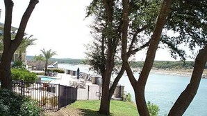 Ein Poolbereich mit Liegestühlen, einer umzäunten Terrasse und Blick auf ein Gewässer.