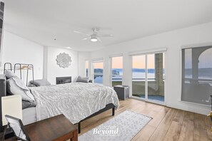 A bedroom with a bed, a ceiling fan, a large window, and a view of the outdoors. - Stately Waterfront Villa on Private Island (Lago Vista)
