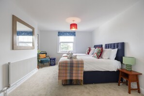 Een slaapkamer met een bed, nachtkastje, lamp, raam, radiator en spiegel.