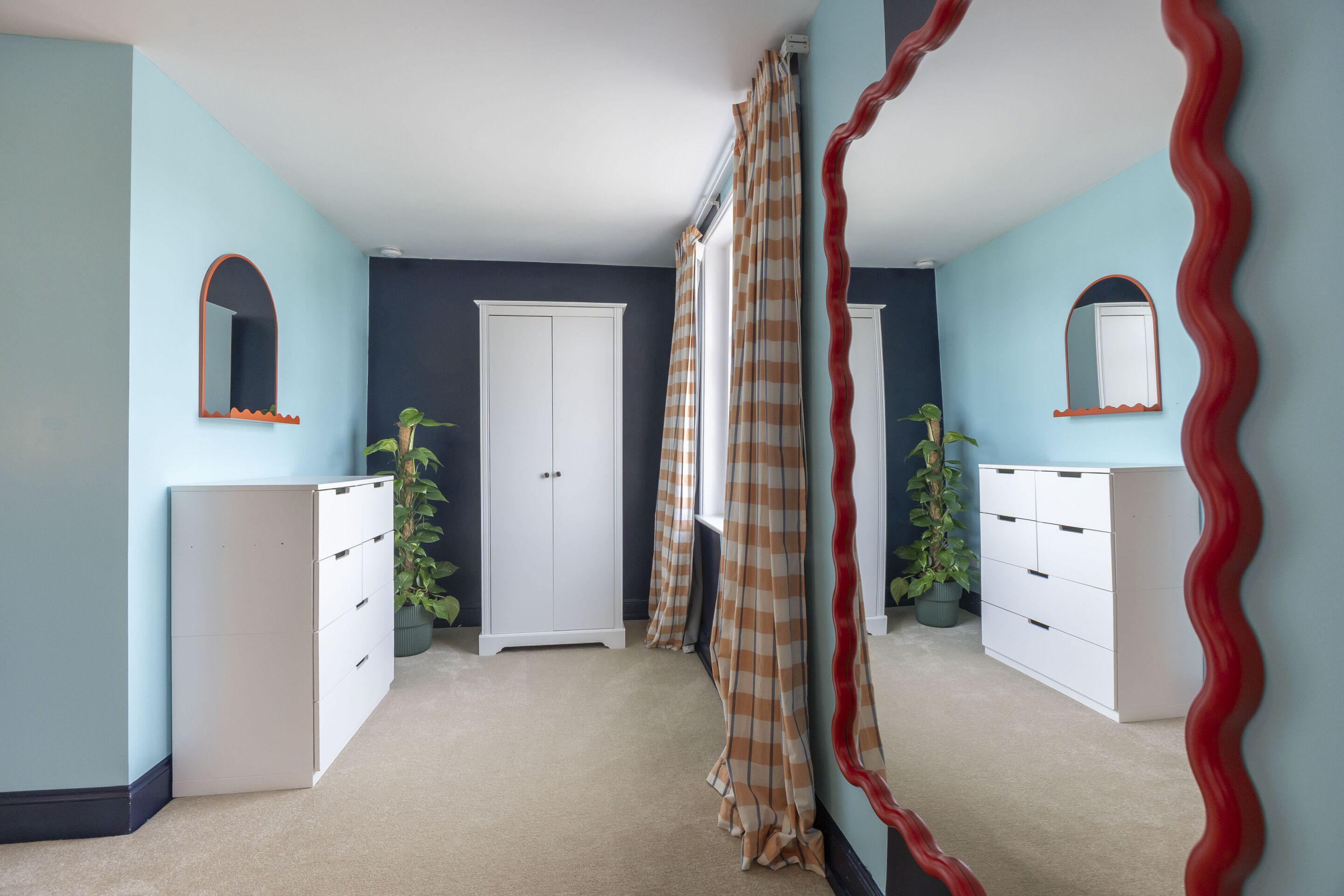 A room with a white dresser, a white door, and a mirror on the wall.