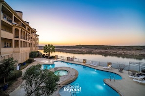 A hotel with a swimming pool, outdoor seating, and a view of a lake at sunset. - Top Floor Waterfront Villa on Private Island (Lago Vista)