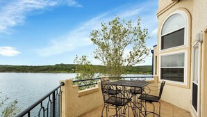 A balcony with a table and chairs overlooking a lake. - Top Floor Waterfront Villa on Private Island (Lago Vista)