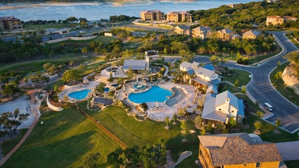 Ein Resort mit mehreren Schwimmbecken, einem großen Gebäude und Blick auf den Ozean.