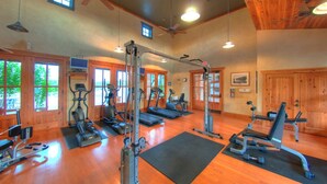 Ein Fitnessstudio mit Trainingsgeräten, Holzböden und großen Fenstern.