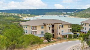 A multi-story hotel with balconies, located near a body of water with boats and a beach in the background. - Lovely Villa in the Hollows, Lake View, 4 Pools (Jonestown)