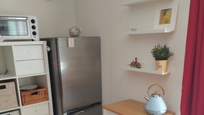 Una cocina compacta con refrigerador, microondas y un pequeño armario con cestas.