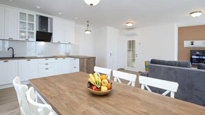 Una cucina moderna con mobili bianchi, un tavolo da pranzo in legno e una ciotola di frutta.