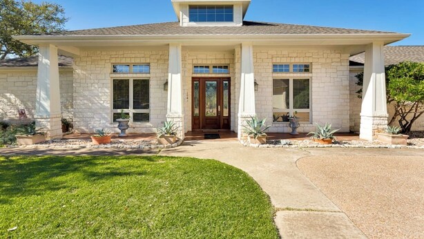 A two-story house with a front porch, large windows, and a stone facade. - Hill Country Estate | 49 Acres | Pool | Game Room | Great Deals! (Lago Vista)