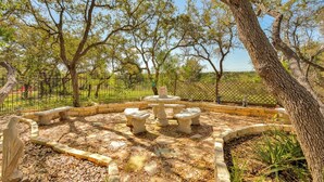 A park with a circular stone seating area, a statue, and a fenced perimeter. - Hill Country Estate | 49 Acres | Pool | Game Room | Great Deals! (Lago Vista)