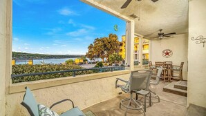 A balcony with a view of a body of water and buildings, furnished with chairs and a table. - Villa 1123 - Villa on Lake Travis (Lago Vista)