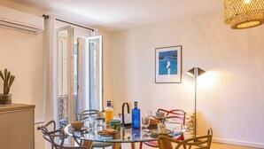 Ein Essbereich mit einem Glastisch, Stühlen, einer Kakteenpflanze, einer Flasche und einem gerahmten Bild an der Wand.