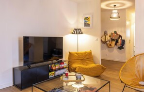A modern living room with a flat-screen TV, a sofa, a coffee table, and a lamp. - Casa Saleccia – Appartement rénové au cœur de Saint-Florent (Saint-Florent)