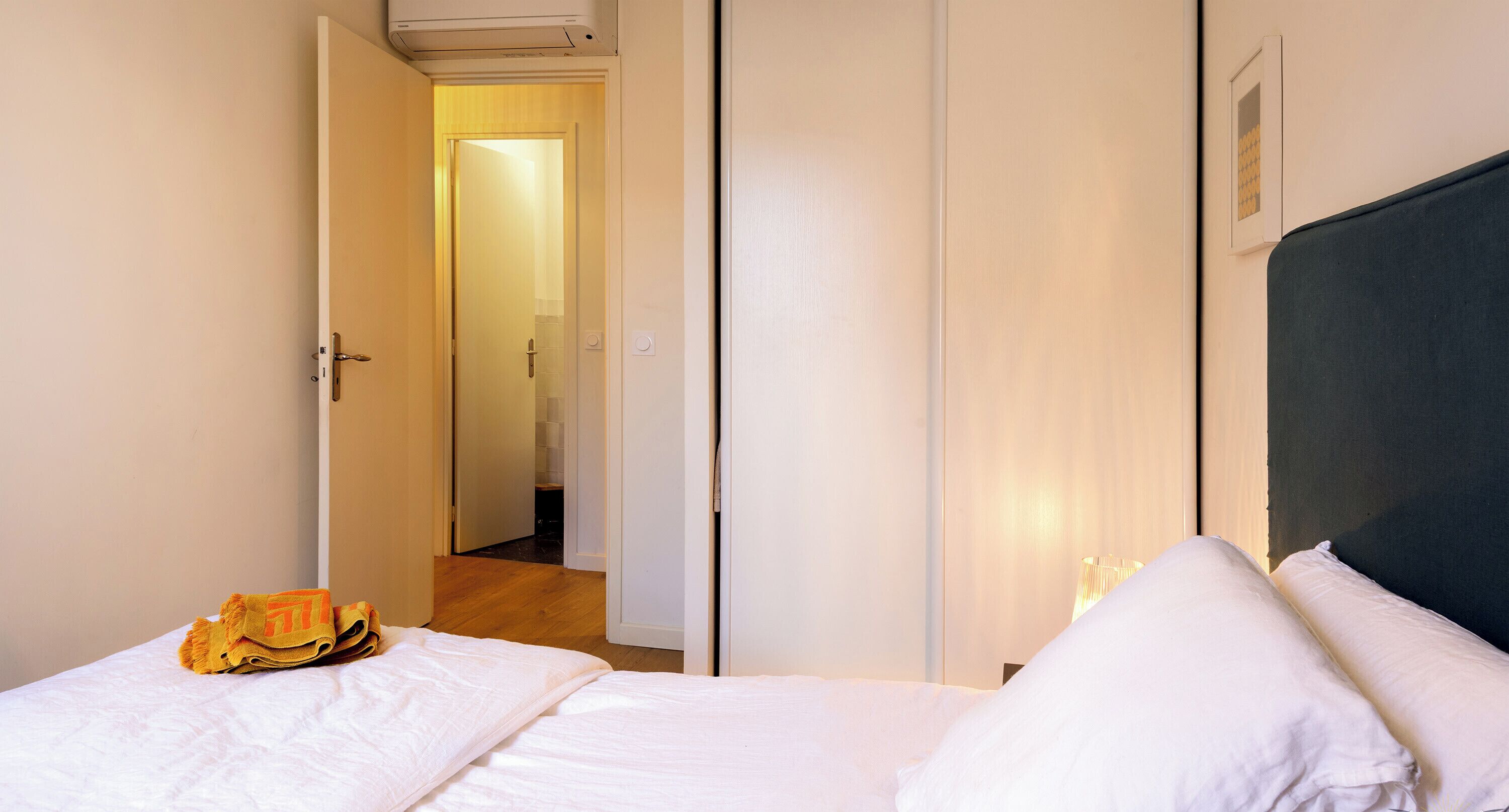 Une chambre d’hôtel avec un lit, une porte donnant sur une autre pièce et un couloir.
