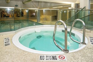 Ein Schwimmbecken mit einem Sprungverbotsschild, einer Glasbarriere und einer Tiefenanzeige.