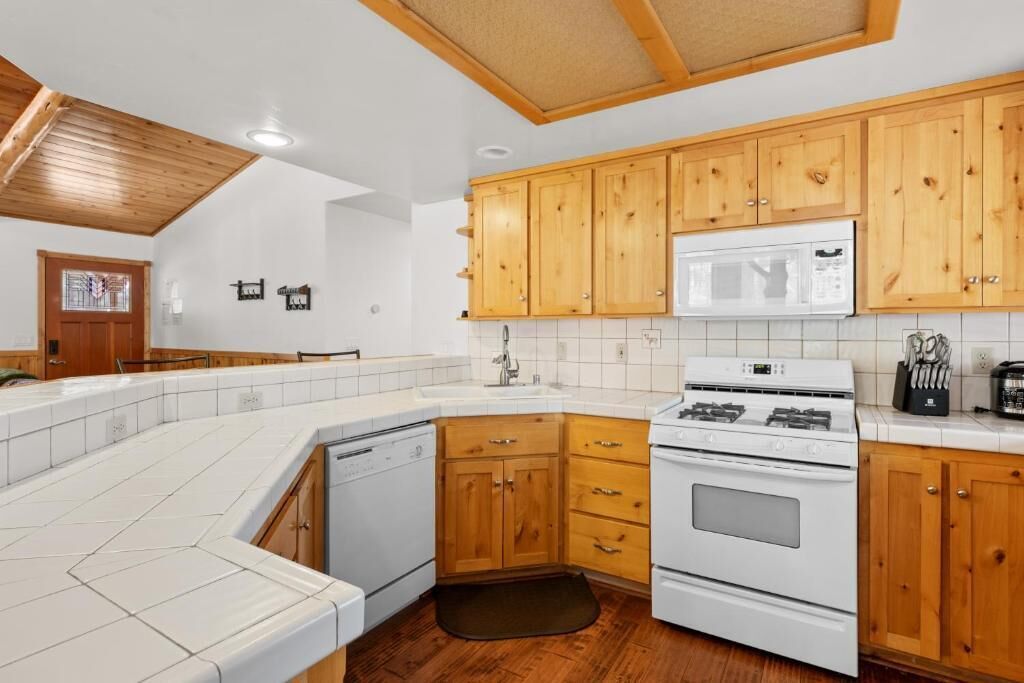 Une cuisine avec des meubles en bois, des appareils électroménagers blancs et un dosseret carrelé.