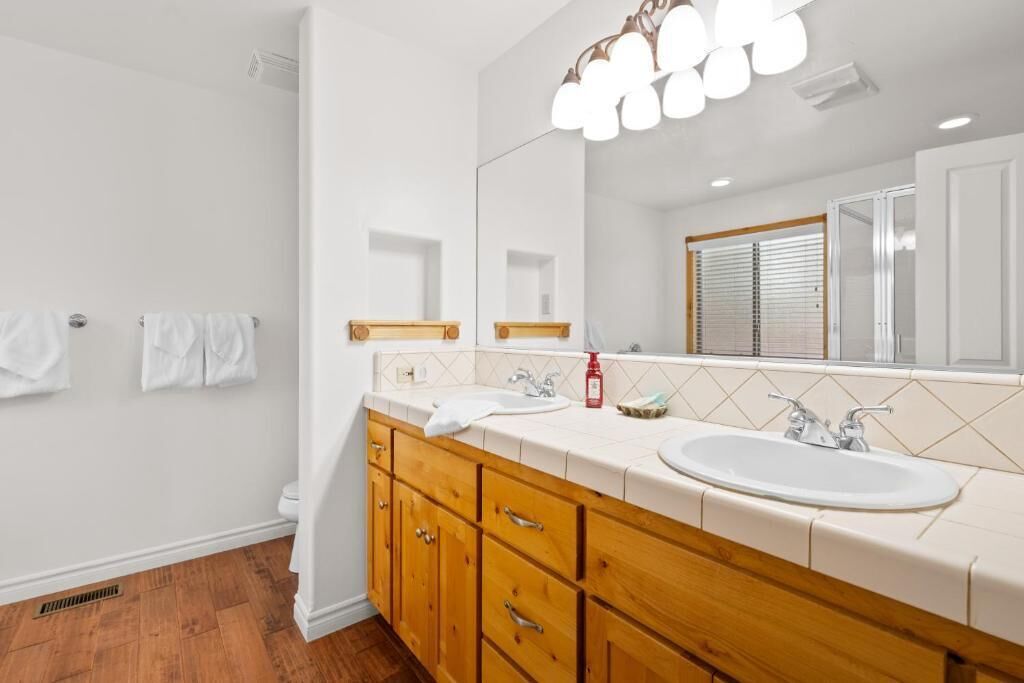 Une salle de bain avec un meuble-lavabo en bois, un grand miroir et un lavabo blanc.