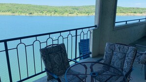 Uma varanda com vista para um lago, uma mesa e duas cadeiras estampadas.