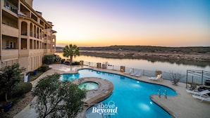 A hotel with a swimming pool, outdoor seating, and a view of a lake at sunset. - UNIT 3321 - Luxury Villa at Island Resort (Lago Vista)