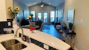 A kitchen with a double sink, a dining area with a table and chairs, and a living room with a sofa and a TV. - UNIT 3321 - Luxury Villa at Island Resort (Lago Vista)