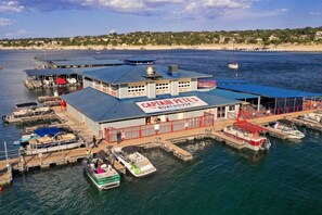 A marina with a building labeled 'Captain Pete's Boathouse' featuring a docked boat, a covered area, and a view of the coastline. - On Lake Time - Point Venture - All Amenities (Point Venture)