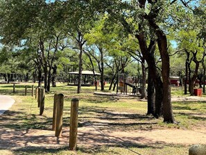 Ein Park mit Bäumen, einem Spielplatz und einem Feldweg.