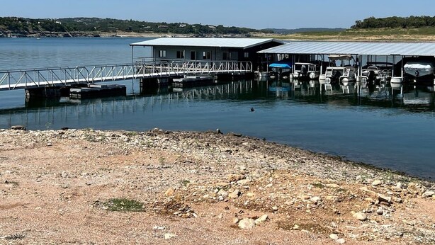 A dock with boats, a pier, and a building with a roof. - The Lazy Lakehouse - All LVPOA Amenities Available (Lago Vista)