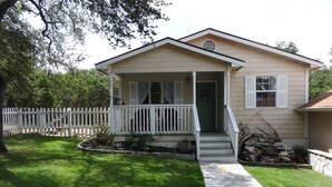 A single-story house with a front porch, a stone pathway leading to the entrance, and a white picket fence. - The Lazy Lakehouse - All LVPOA Amenities Available (Lago Vista)