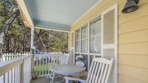 A covered porch with a table and chairs, a white picket fence, and a sign that reads 'LAKE HOUSE.' - The Lazy Lakehouse - All LVPOA Amenities Available (Lago Vista)
