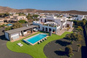 A modern villa with a swimming pool, outdoor seating, and a view of the surrounding neighborhood. - Villa Ballena Azul - Nine Bedroom Villa, Sleeps 21 (Teguise)