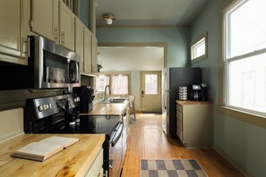 A kitchen with a stove, microwave, and refrigerator. - The Single Barrel - Deck, Fire Pit, Hot Tub, Games (Louisville)